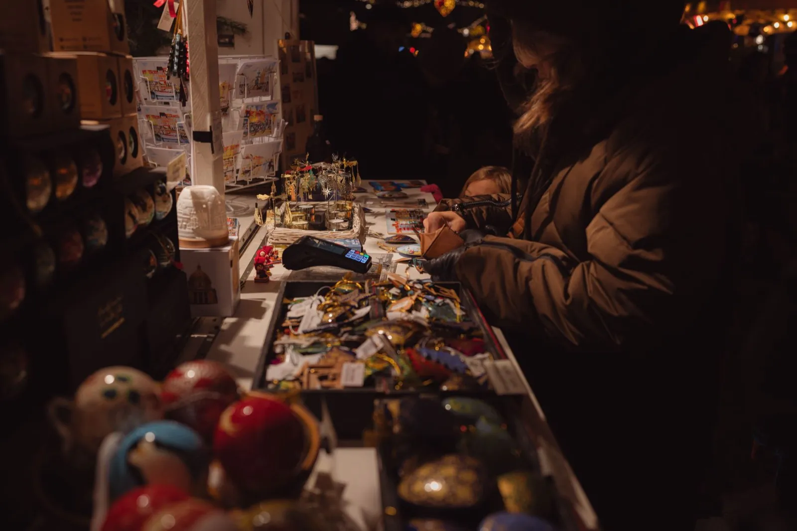 夜間市集攤位上擺滿手作小物與明信片,一位客人正在挑選,小蝸牛市集
